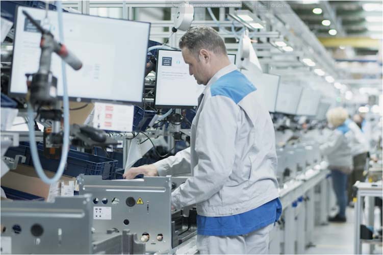 Ein Produktionsmitarbeiter montiert in einer One-Piece-Flow-Montagelinie Wärmepumpen und wird von der papierlosen Montage-Software von Scable unterstützt.